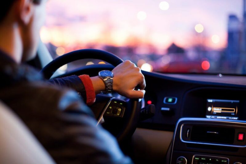 laki-laki sedang menyetir / mengendarai mobil dengan menggunakan jam tangan