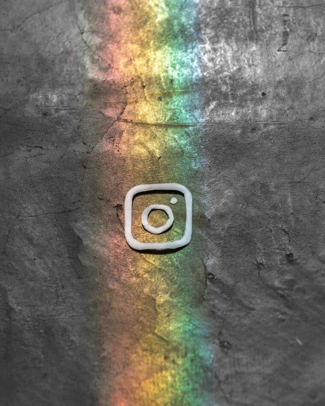 logo instagram pelangi hitam putih diatas batu