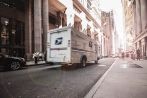 cara mencari supplier yang baik dan terpercaya, kendaraan putih pengangkut barang/ paket sedang mengantar pesanan pelanggan dengan truk, melintas dengan cepat di jalan raya
