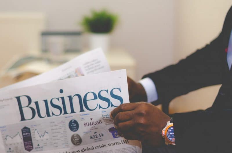 usaha sampingan di rumah, foto tangan sedang memegang koran bertuliskan business atau bisnis
