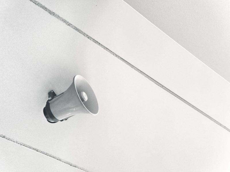 tips membuat kata-kata promosi dan contohnya, foto hitam putih toak speaker pengeras suara menempel di dinding