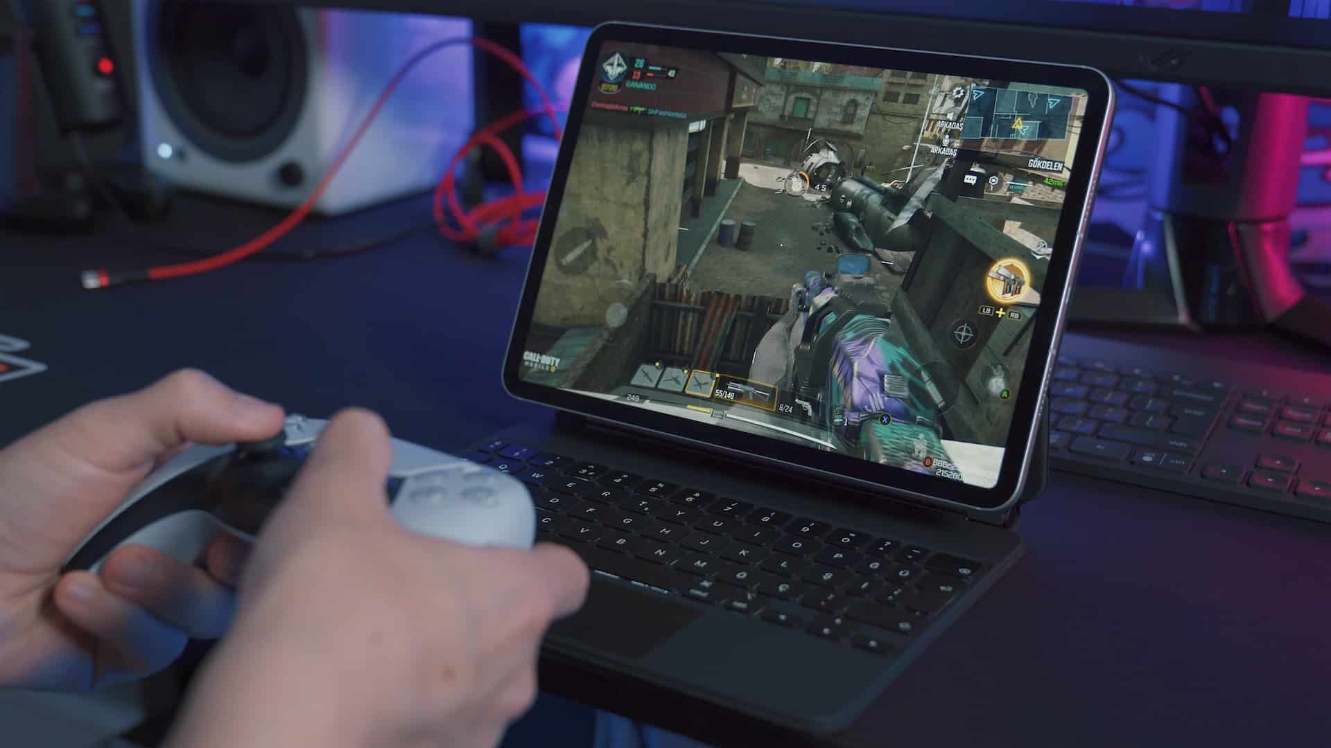 gambar tangan sedang memegang console game dan bermain sebuah permainan di laptop